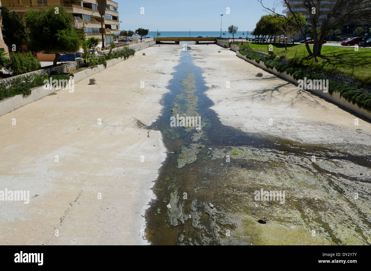 Dry urban concrete river bed receding into distance towards Mediterranean sea, Costa del Sol, Fuengirola, Andalusia, Spain Stock Photo