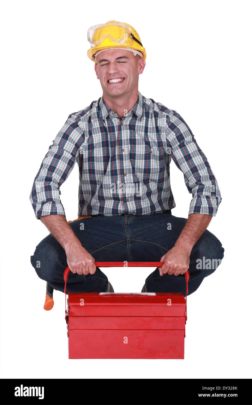 Tradesman struggling to lift his toolbox Stock Photo