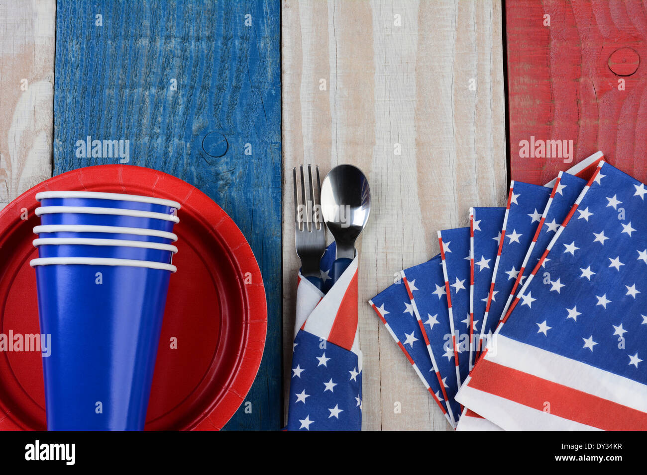High angle photo of a Fourth of July picnic table setting. The red white and blue items are on a wood table Stock Photo