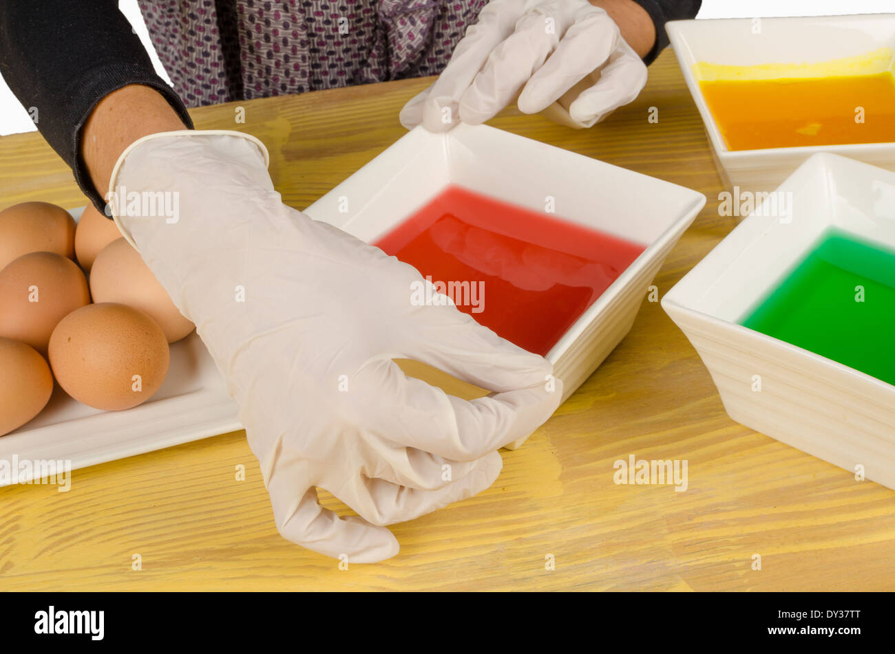 Hands with gloves getting ready to dye Easter eggs Stock Photo