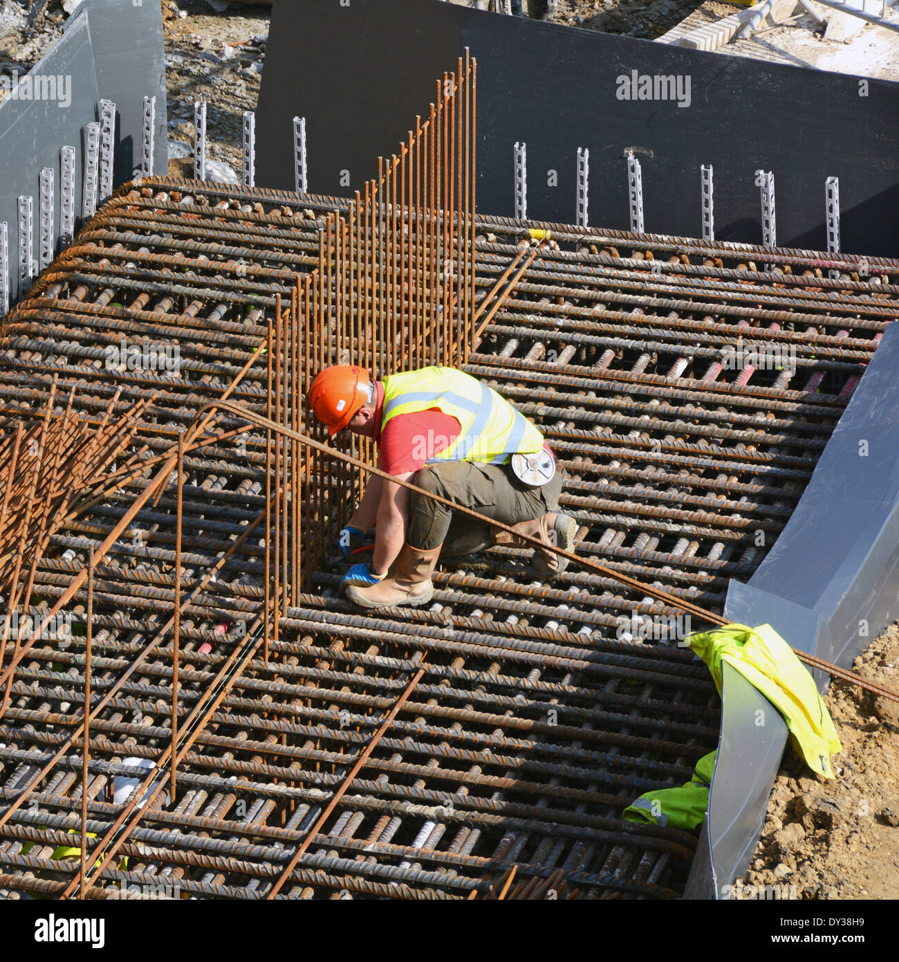 Construction site steelfixer tying steel reinforcement cage together as part of foundations for new building London England UK Stock Photo