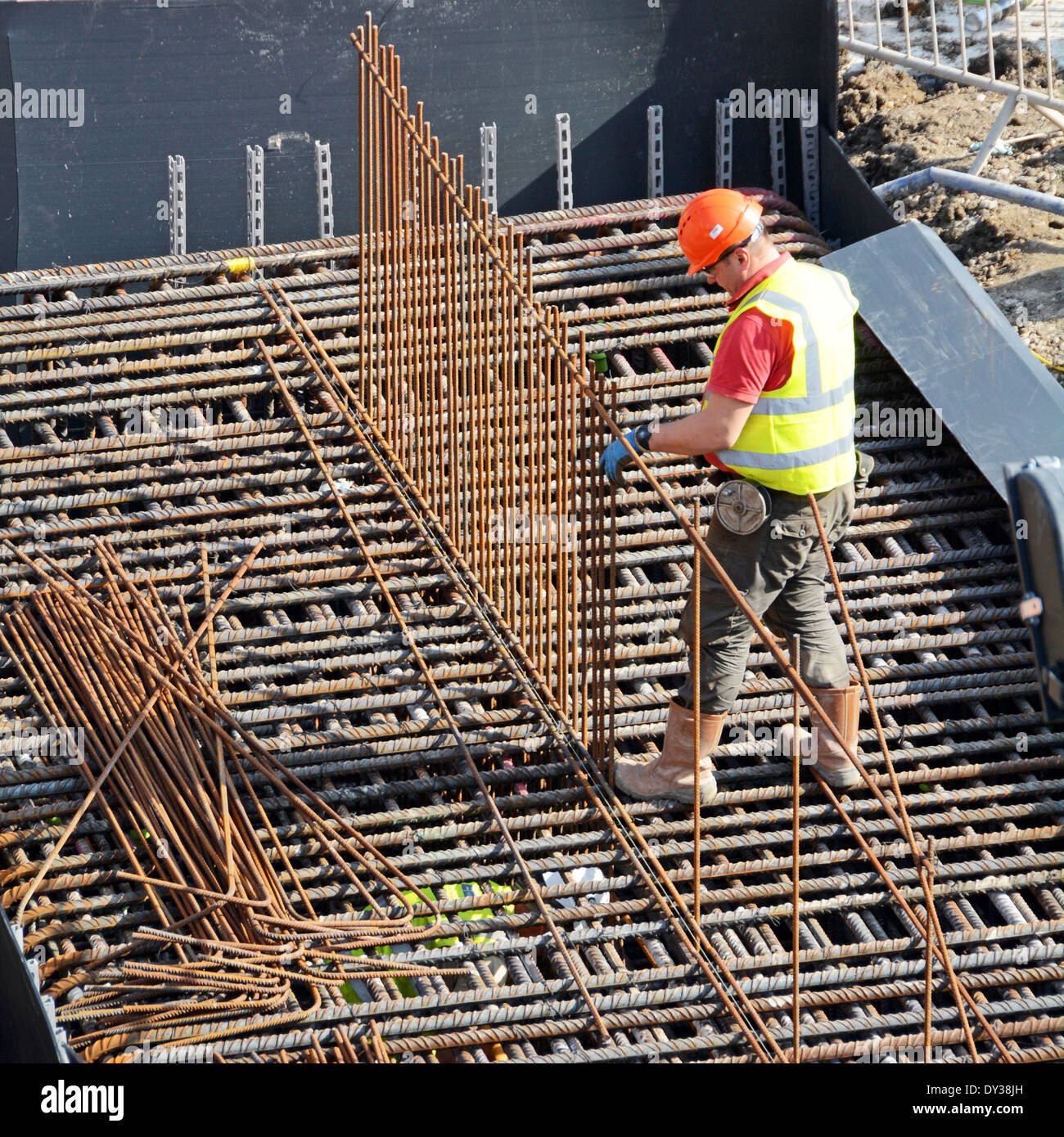 Steelfixer tying steel reinforcement cage together as part of foundations for new building Stock Photo