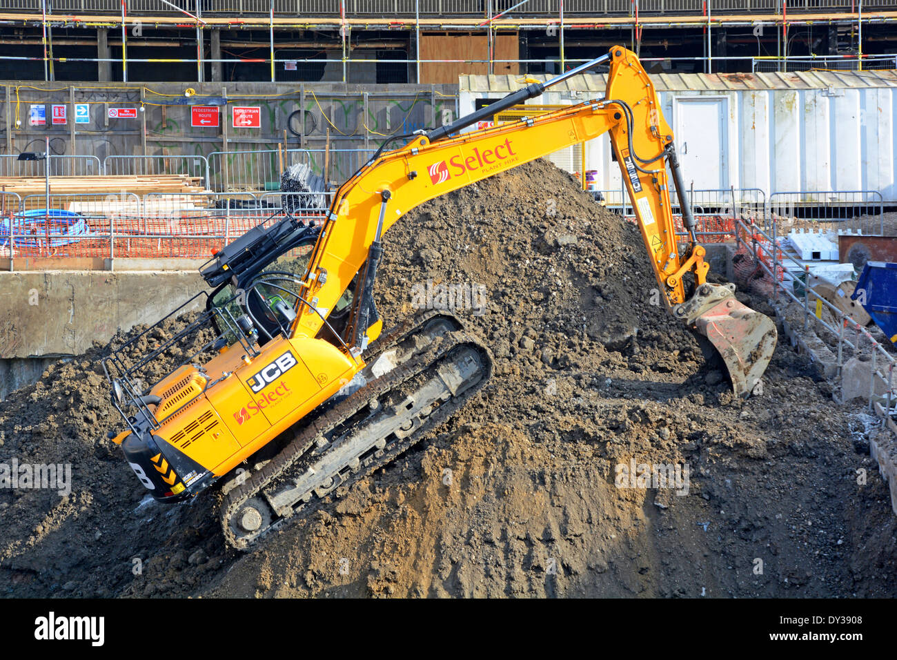 J.C. Bamford (JCB) tracked excavator back actor & loader at work climbing back up to top of spoil heap on construction building site London England UK Stock Photo