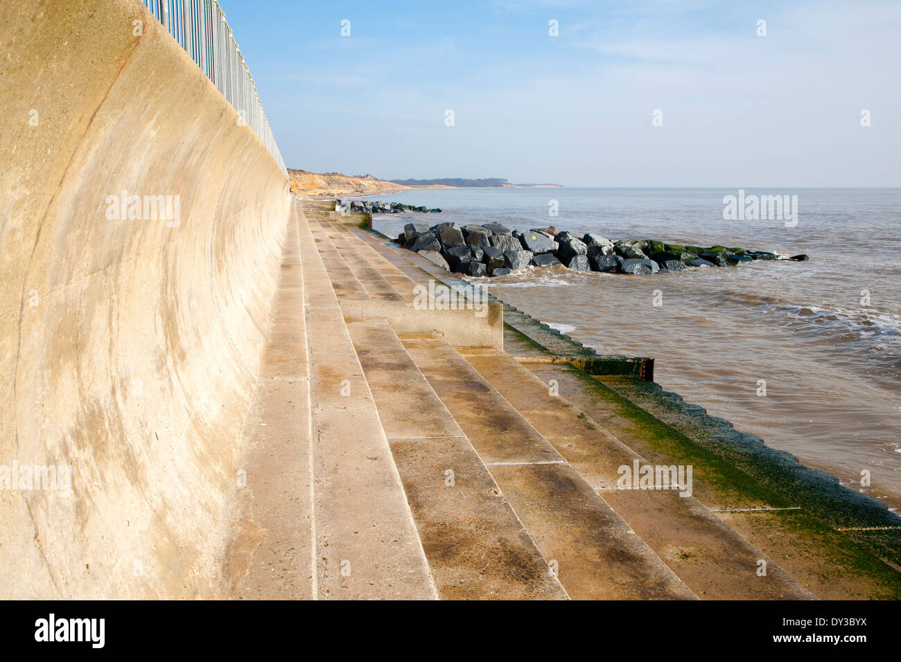 Curved wave return sea wall, steps and rock armour groynes, forming coastal defences at Southwold, Suffolk, England Stock Photo