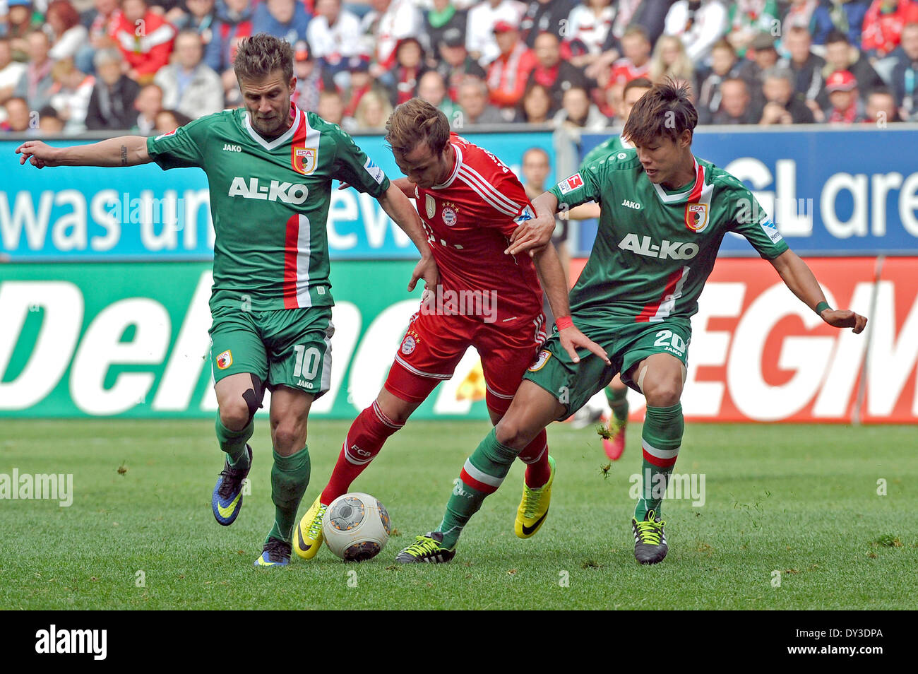Augsburg, Germany. 05th Apr, 2014. Augsburg's Daniel Baier (L) and Jeong-Ho Hong and Munich's Mario Goetze (C) vie for the ball during the Bundesliga Soccer match between FC Augsburg and FC Bayern Munich at the SGL-Arena in Augsburg, Germany, 05 April 2014. Photo: Stefan Puchner/dpa (ATTENTION: Due to the accreditation guidelines, the DFL only permits the publication and utilisation of up to 15 pictures per match on the internet and in online media during the match.)/dpa/Alamy Live News Stock Photo