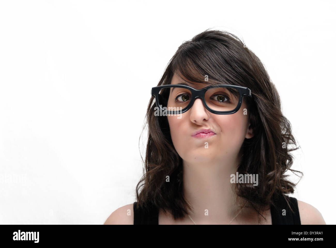 A young woman with long dark hair wearing comical dark eyeglasses makes a funny face. Stock Photo