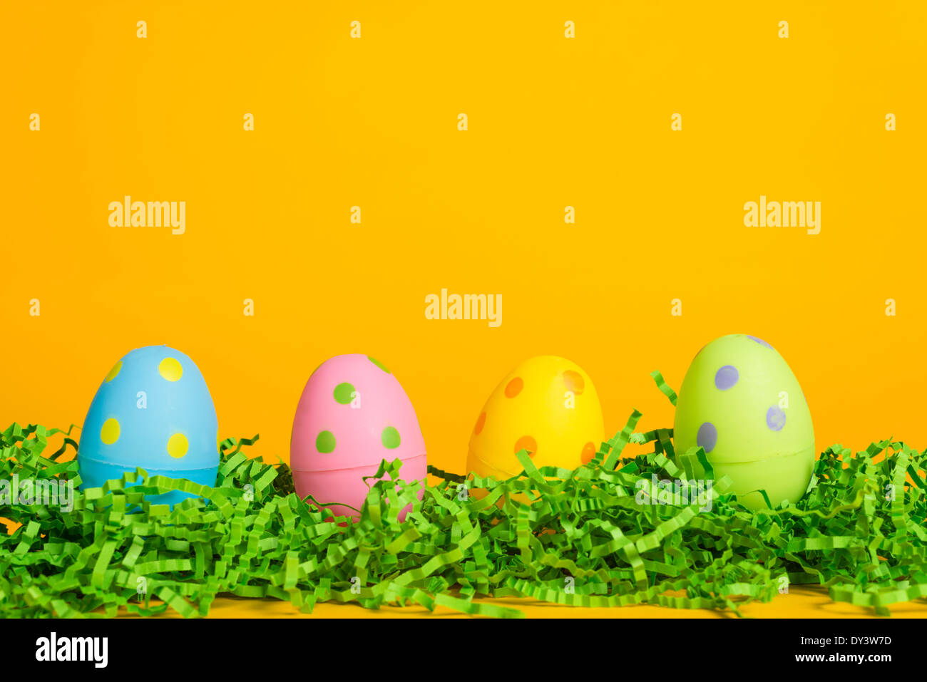4 assorted colored Easter eggs on a yellow background Stock Photo