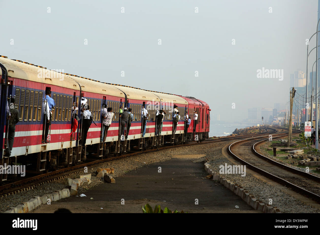 Train at Bambalapitiya Railway station with male passengers hanging out of  carriages, in Colombo, Sri Lanka Stock Photo - Alamy