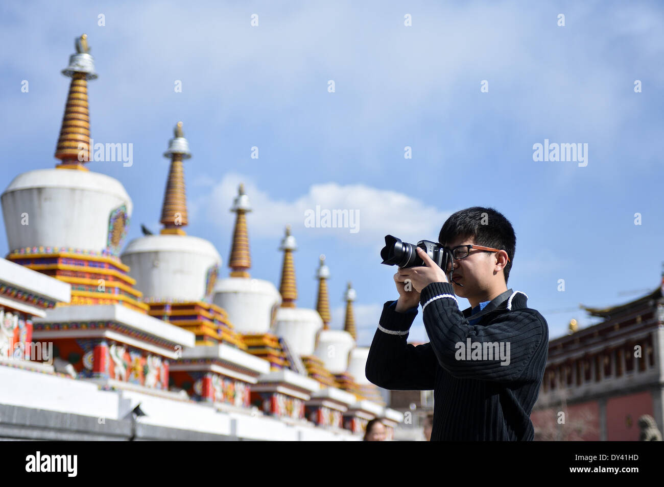 Huangzhong County, China's Qinghai Province. 6th Apr, 2014. A tourist taks photos in the Kumbum Monastery in Huangzhong County of Xining, capital of northwest China's Qinghai Province, April 6, 2014. The Kumbum Monastery is a main destination for Tibetan Buddhist pilgrims. It is also a major tourist attraction in Qinghai, which features splendid religious murals, Thangka appliques and butter sculptures. © Wu Gang/Xinhua/Alamy Live News Stock Photo