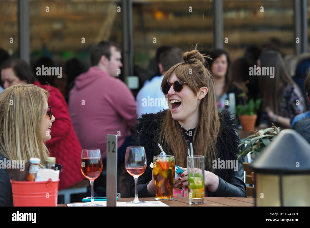 People taking advantage of the hot British weather to socialize with friends, drinking and eating by the Thames river, London. Stock Photo