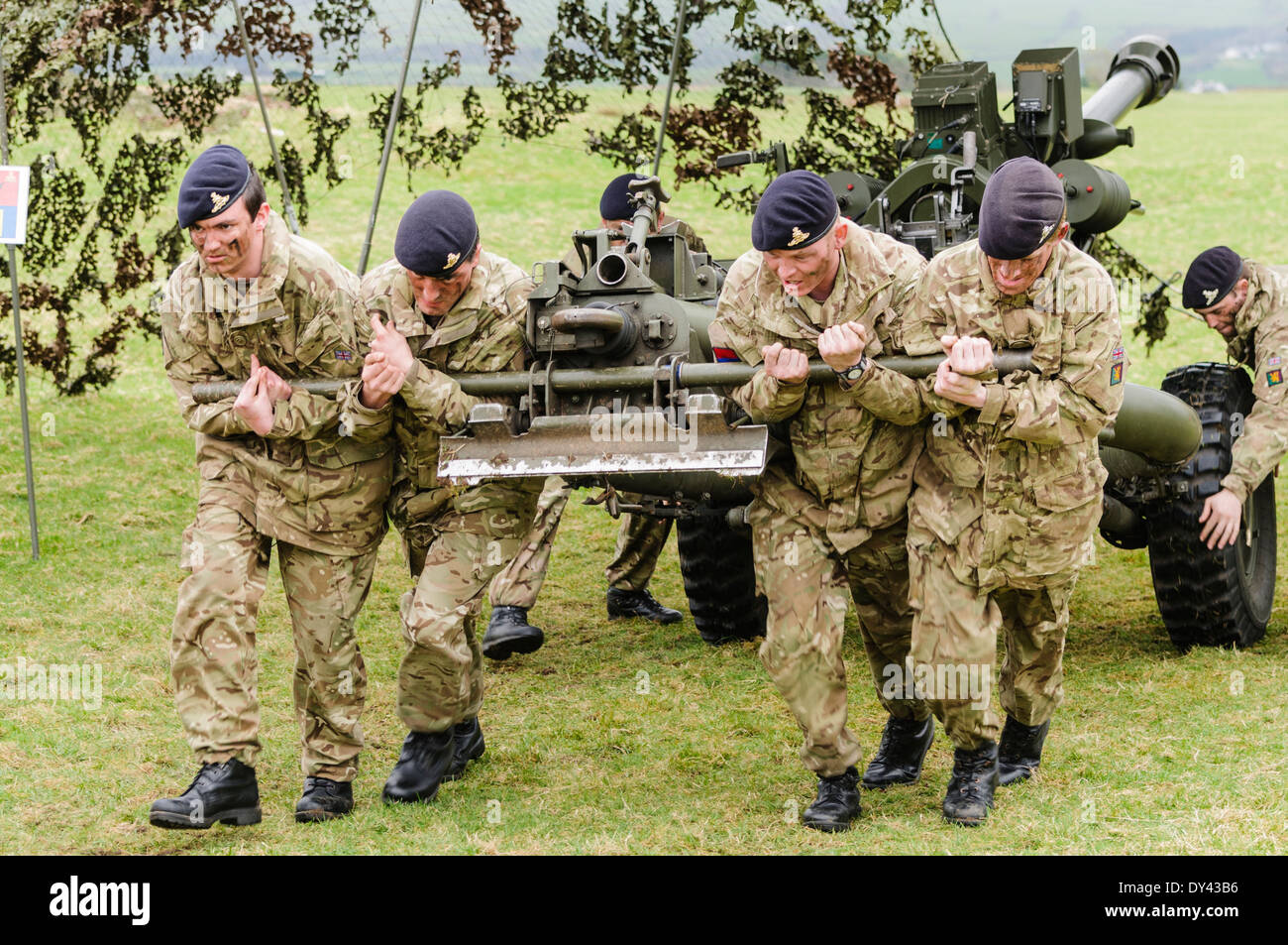 Soldiers from the Royal Artillery strain to pull a 105mm Light