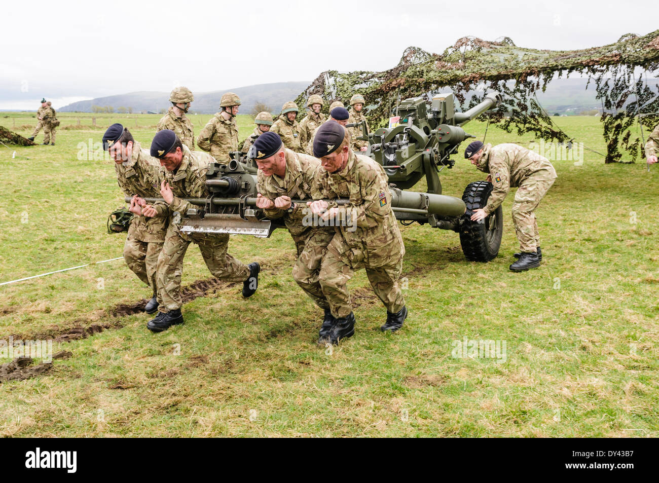 Soldiers from the Royal Artillery strain to pull a 105mm Light Artillery Gun Stock Photo