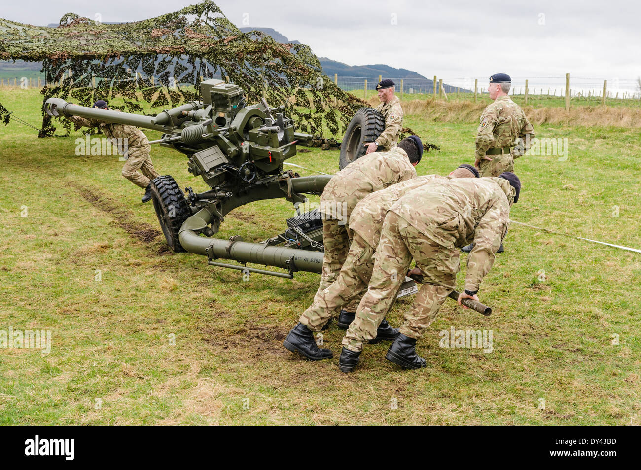 Soldiers from the Royal Artillery lift a 105mm Light Artillery Gun to enable a colleague to remove a wheel Stock Photo