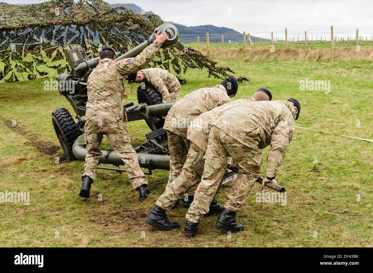 Soldiers from the Royal Artillery lift a 105mm Light Artillery Gun to enable a colleague to remove a wheel Stock Photo
