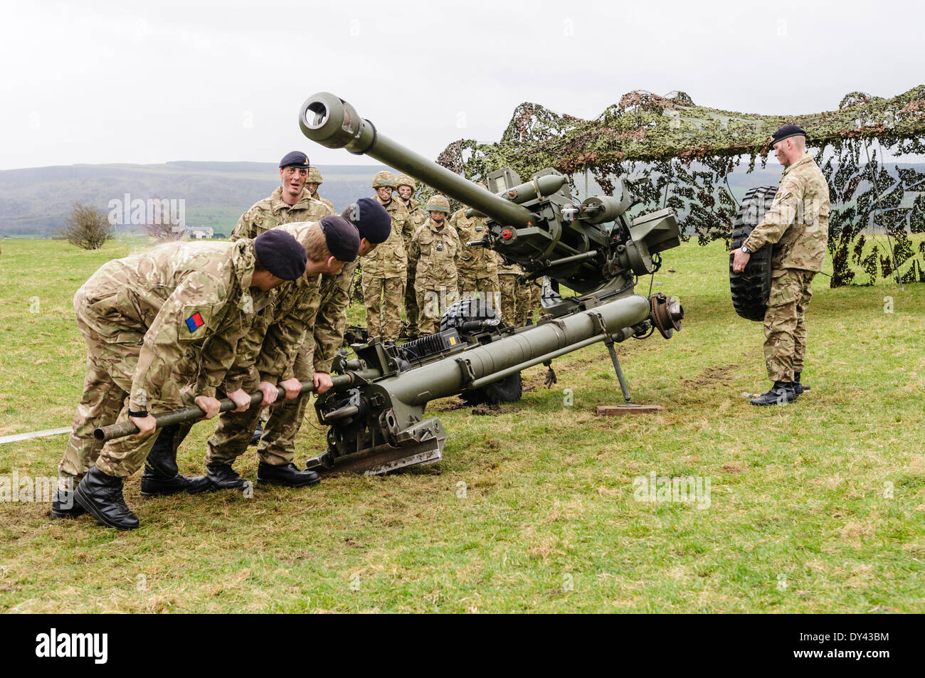 Soldiers from the Royal Artillery lift a 105mm Light Artillery Gun to enable a colleague to fit a wheel ready for transport Stock Photo