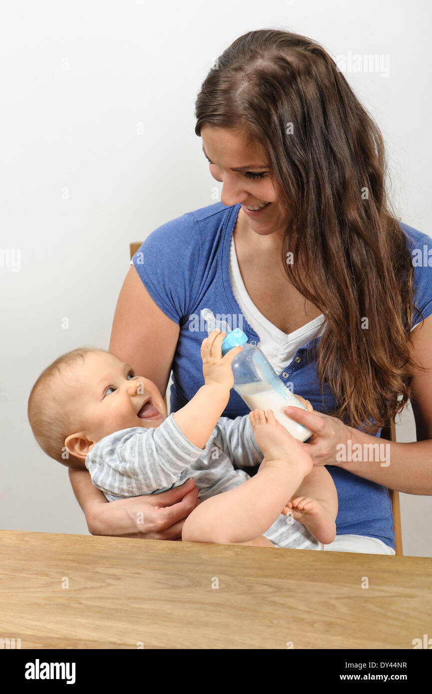 Mother feeds seven month old baby with milk bottle. She cradles the