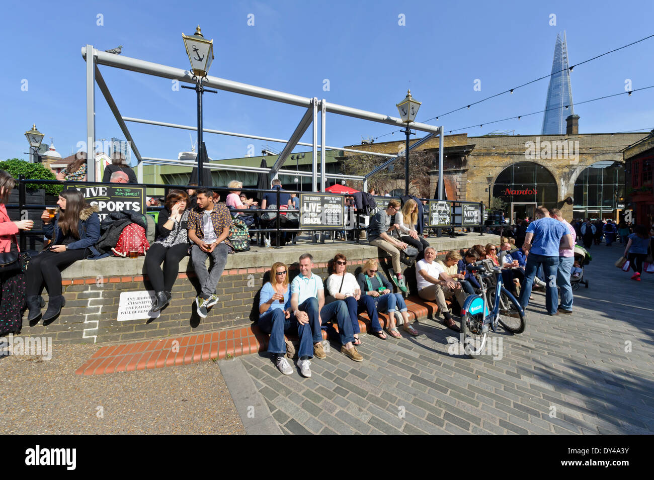 People taking advantage of the hot British weather to socialize with friends, drinking and eating by the Thames river, London. Stock Photo