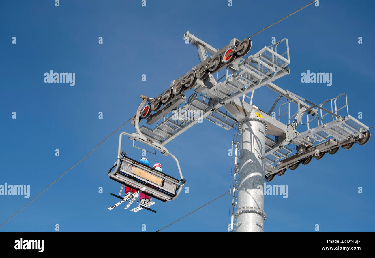 Skiers on chairlift against a blue sky Stock Photo
