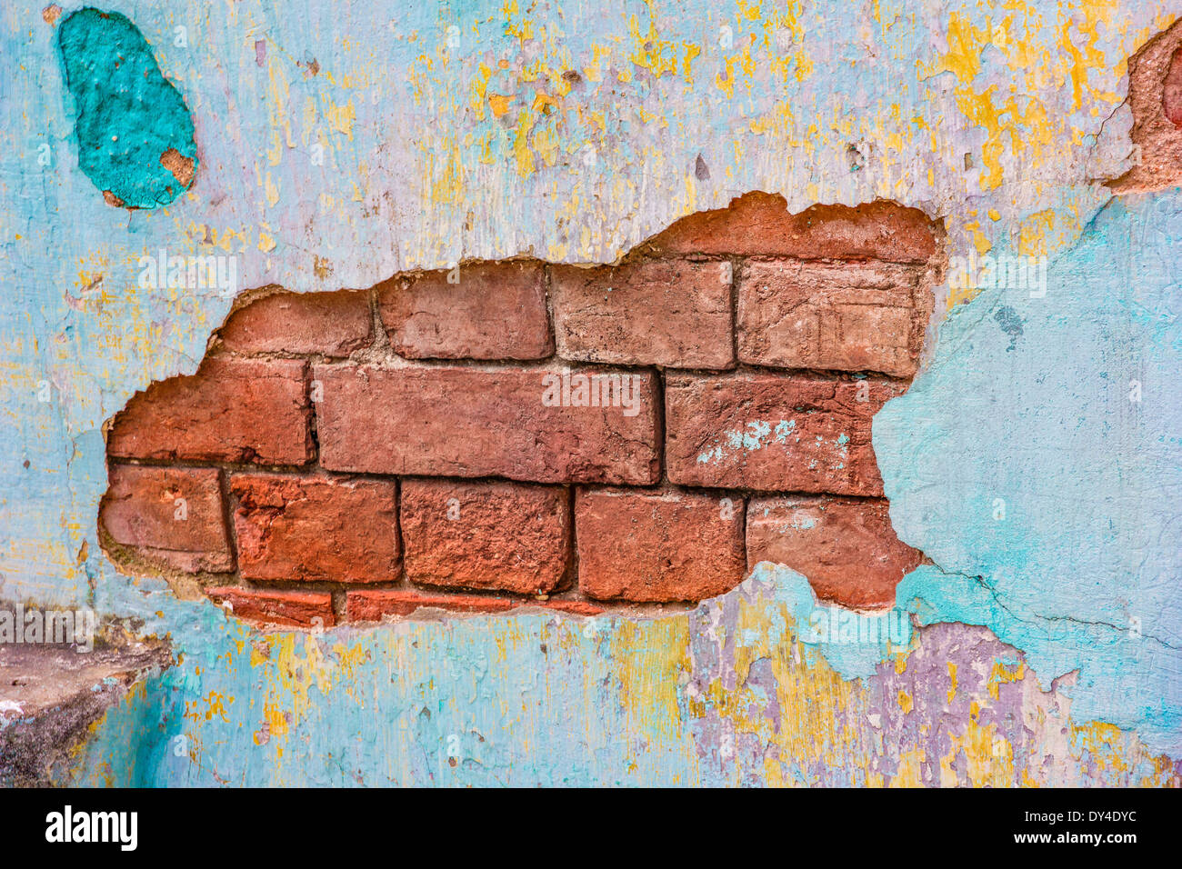 Colorfully painted plaster chipping off a brick wall Stock Photo