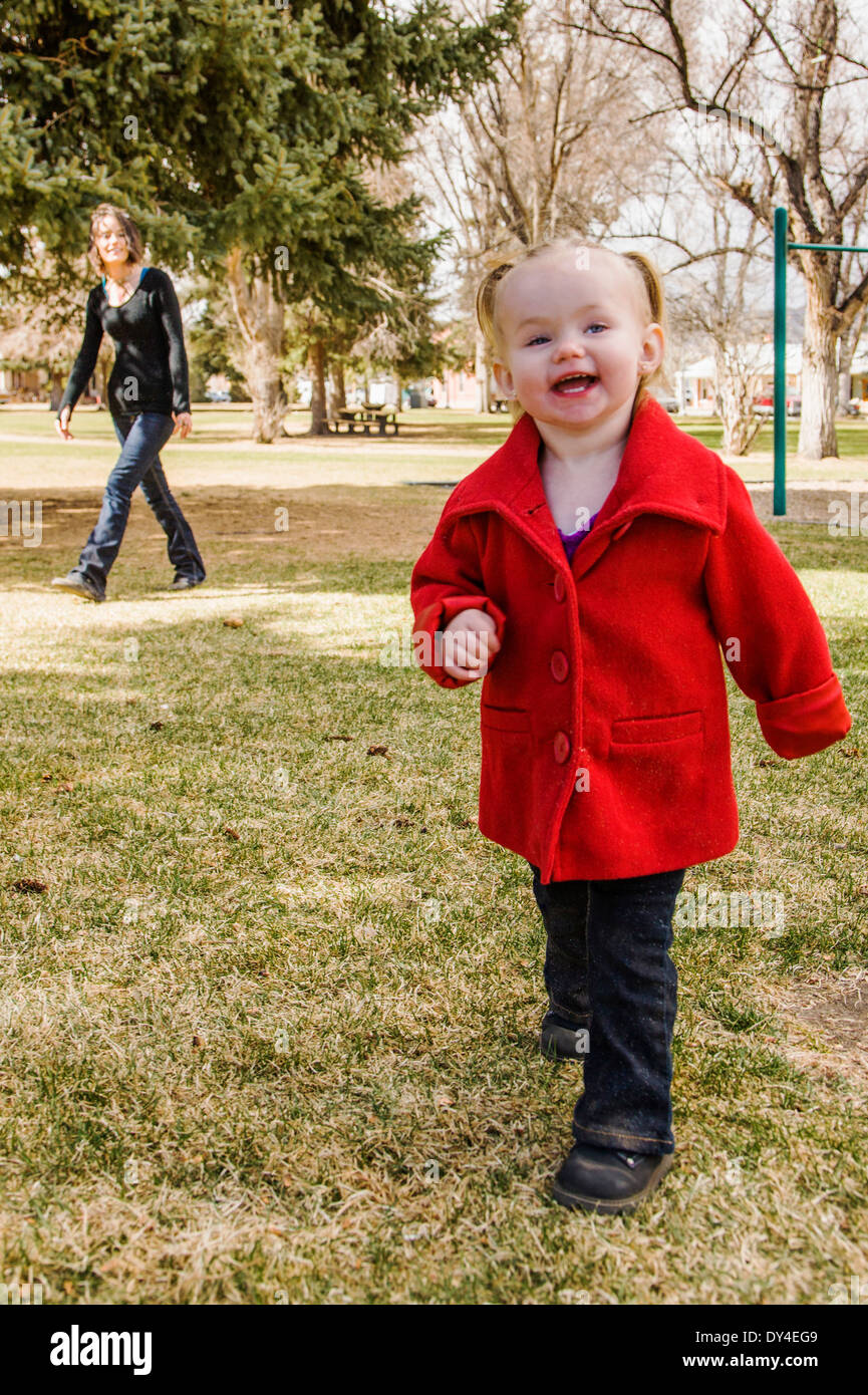 Beautiful young mother playing with adorable, cute 16 month baby girl on park playground Stock Photo