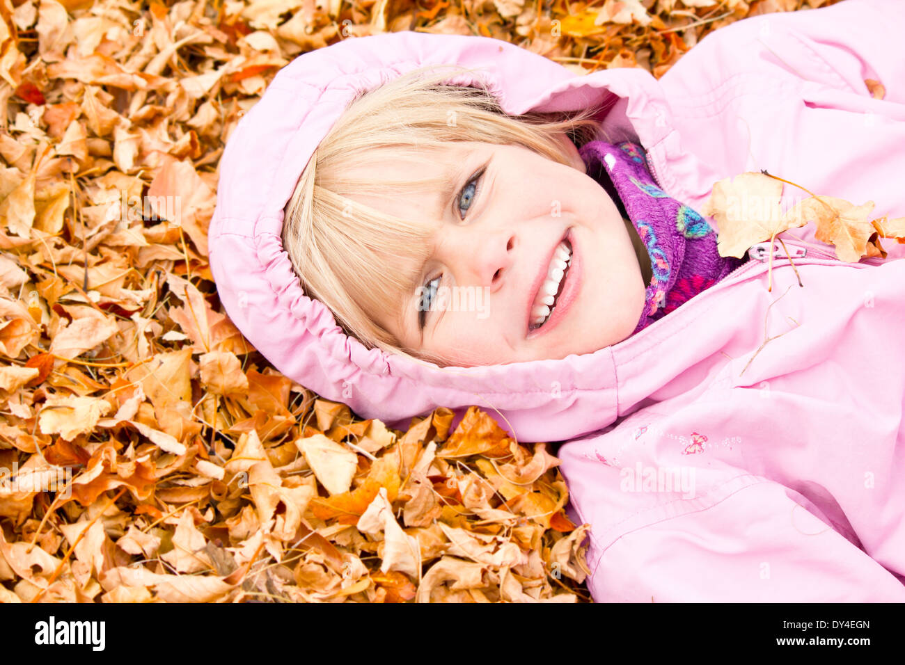 Little Girl Lying in Autumn Leaves with a big smile Stock Photo - Alamy