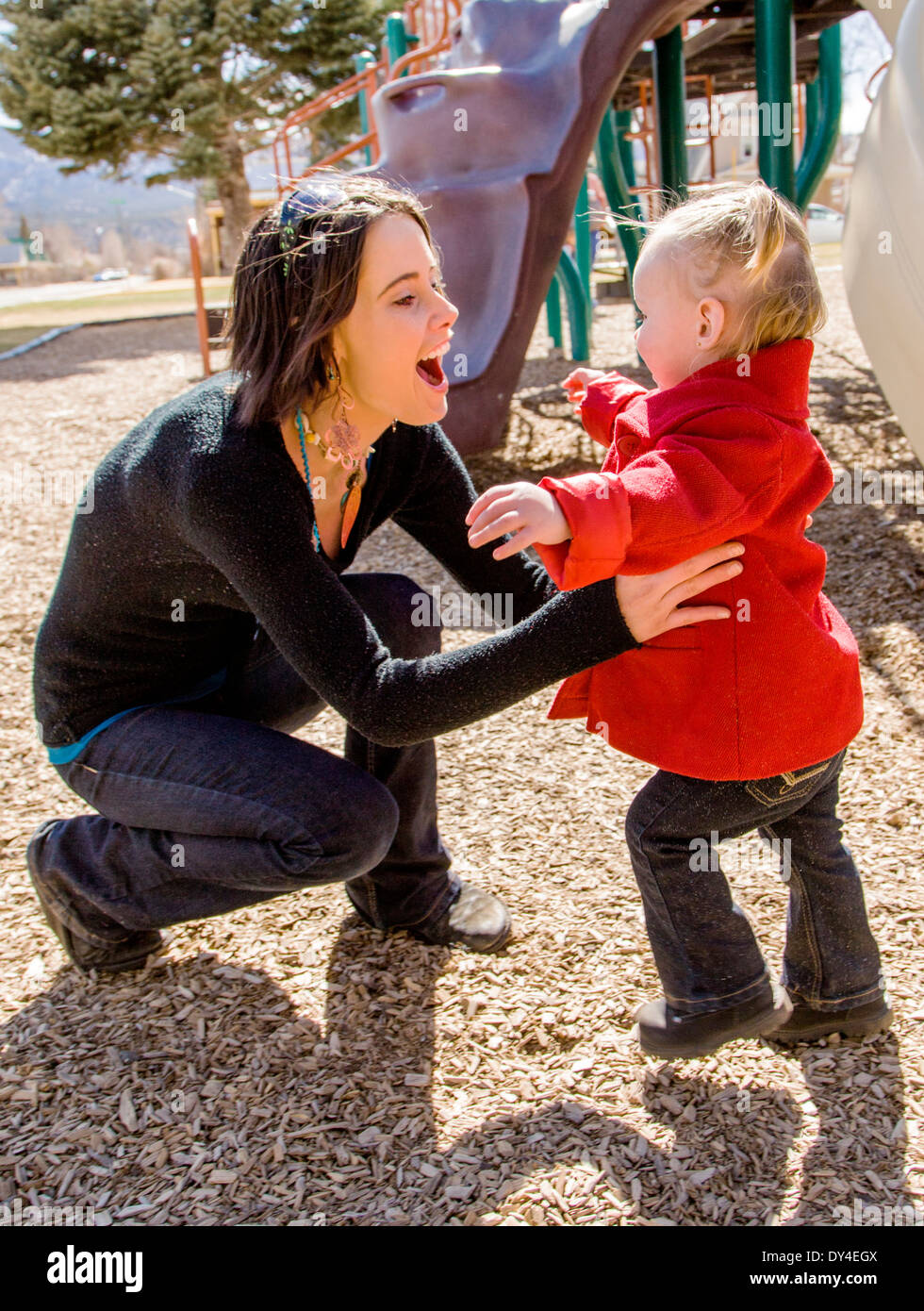 Beautiful young mother playing with adorable, cute 16 month baby girl on park playground Stock Photo