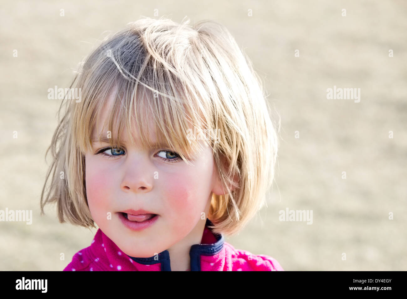 Little girl with wary look and tongue sticking out Stock Photo