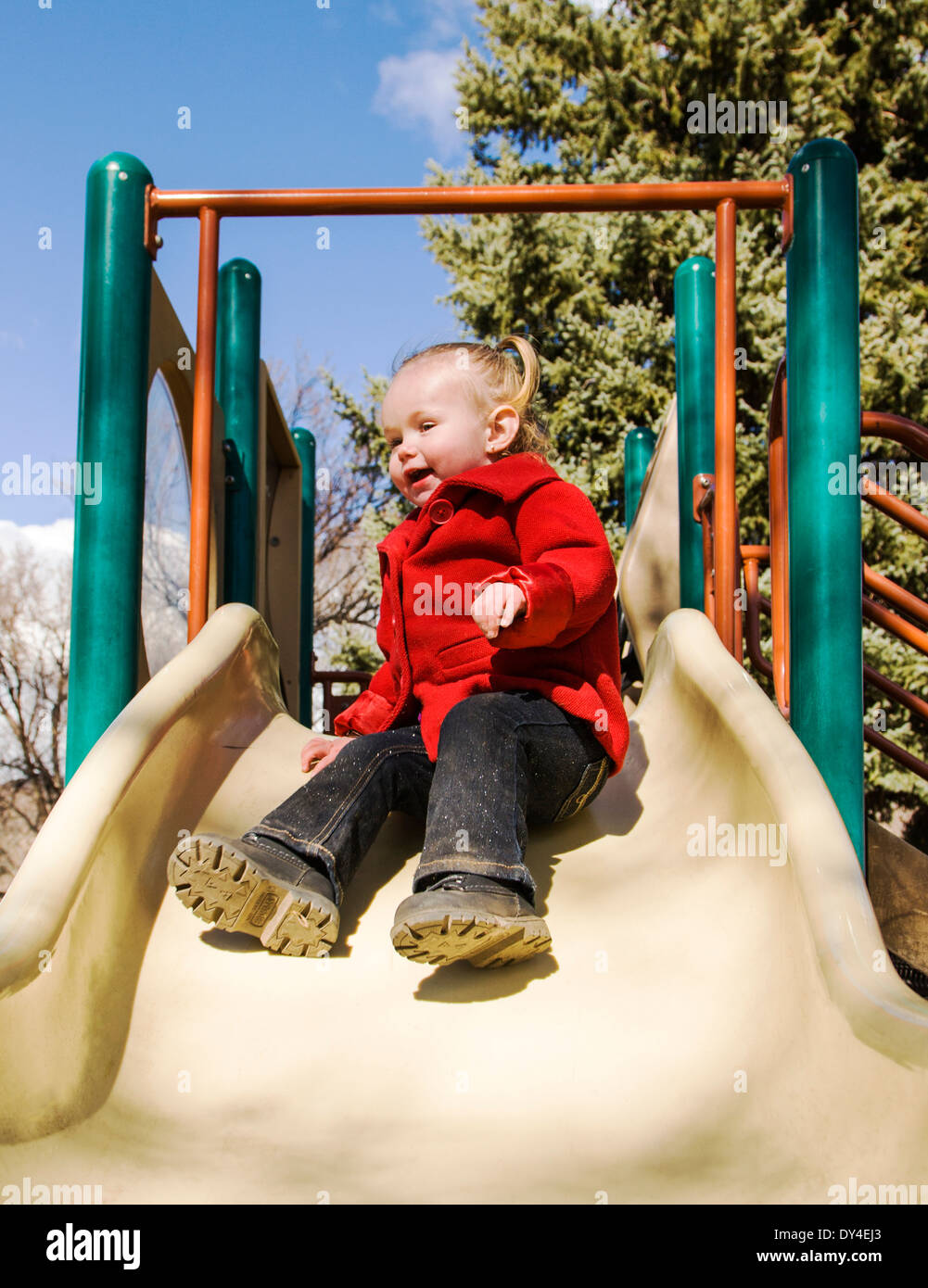 Adorable, cute 16 month little girl playing on a park sliding board Stock Photo