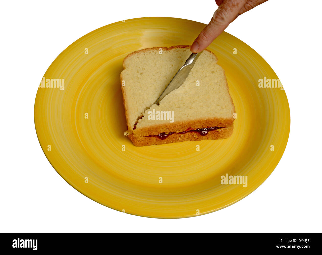 slicing peanut butter and jelly sandwich with a knife on a yellow plate