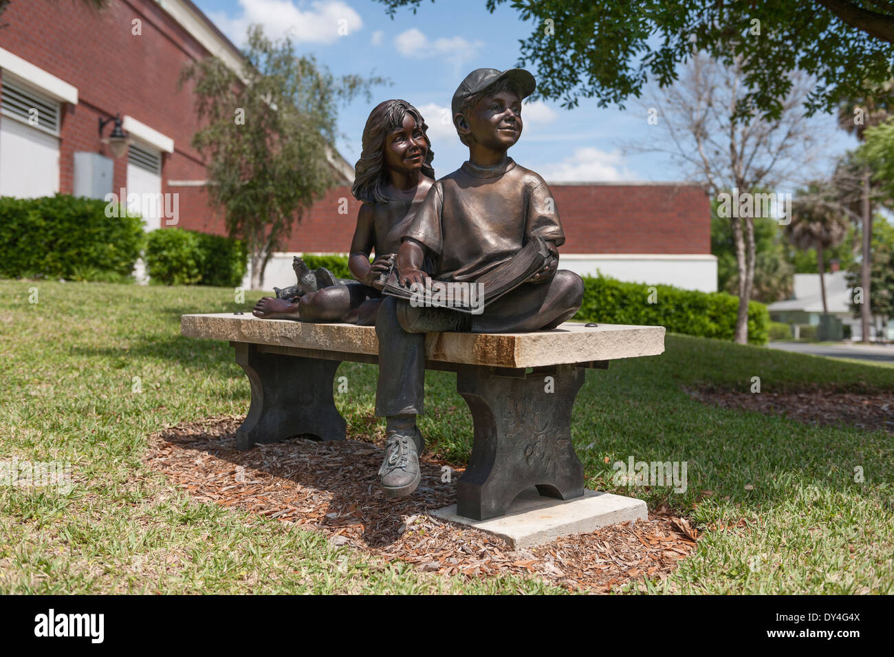 Bronze statue of children reading a book on a bench outside the