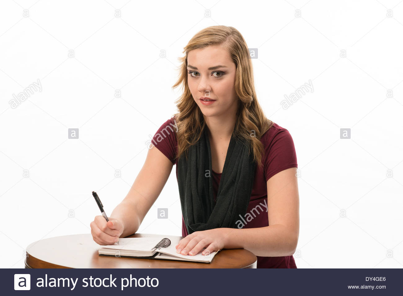 Teen Girl Sitting At A Desk Writing In A Note Book Stock Photo