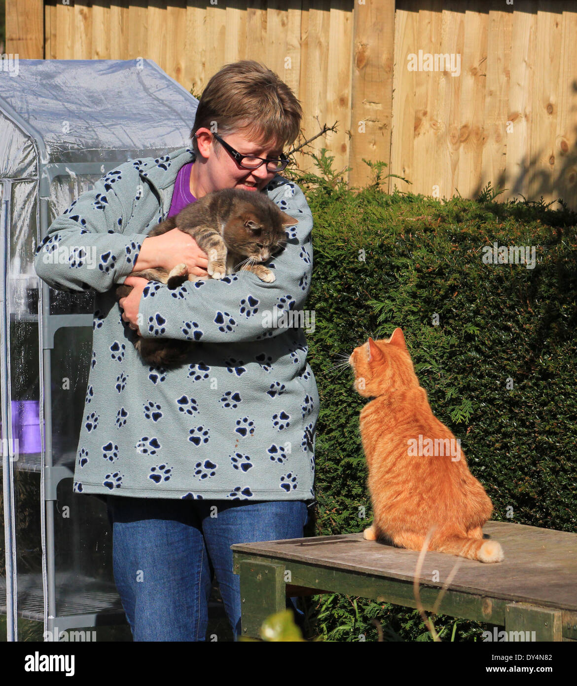 Woman in garden with two cats Stock Photo