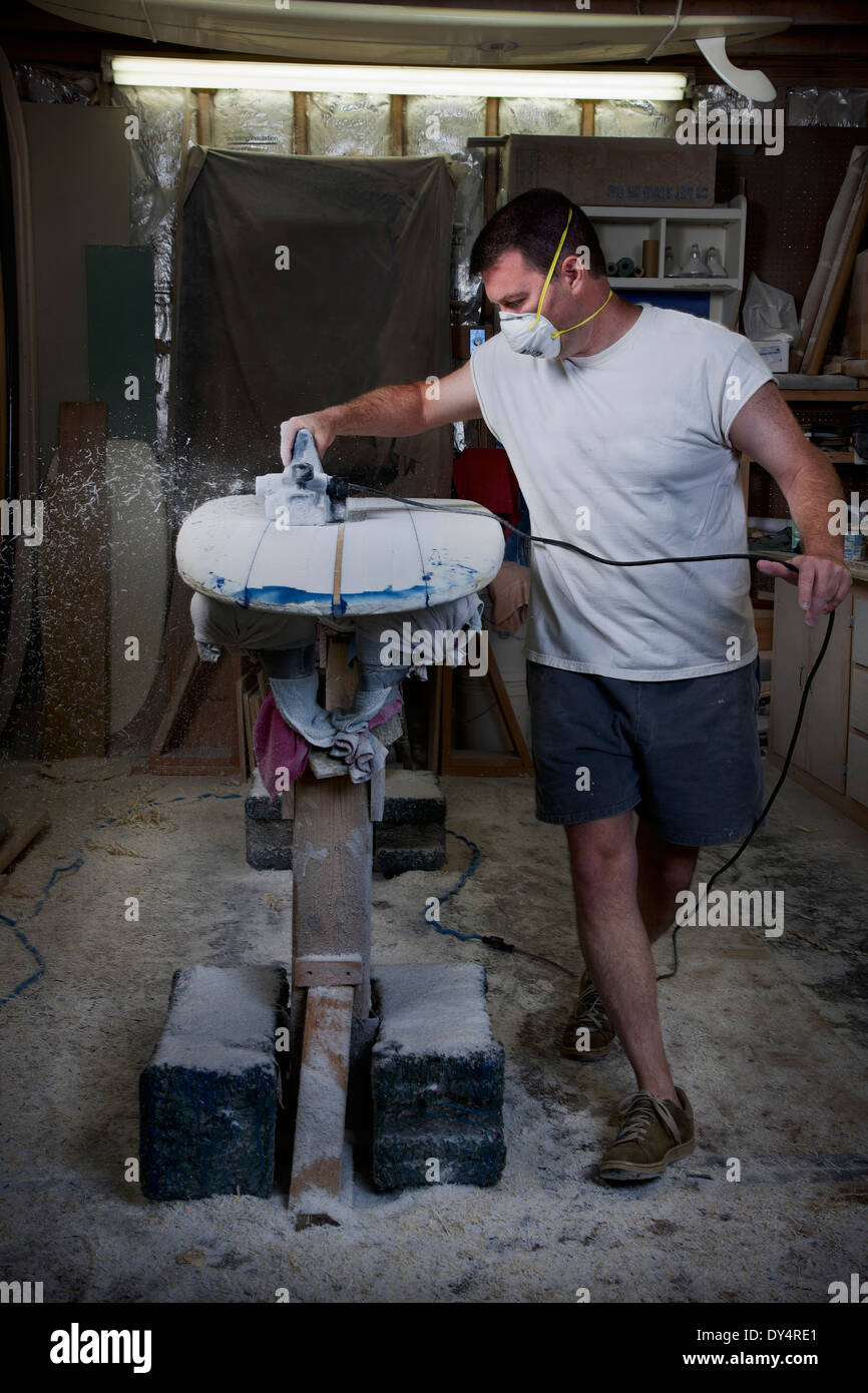 Mature man sanding a surfboard in his garage Stock Photo Alamy