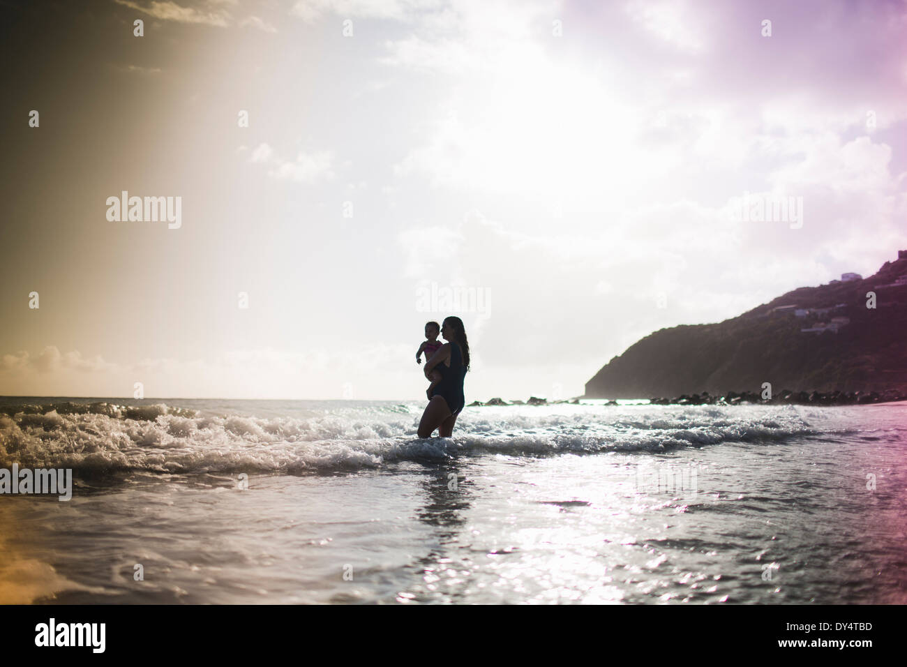 Mother holding daughter, paddling in sea Stock Photo
