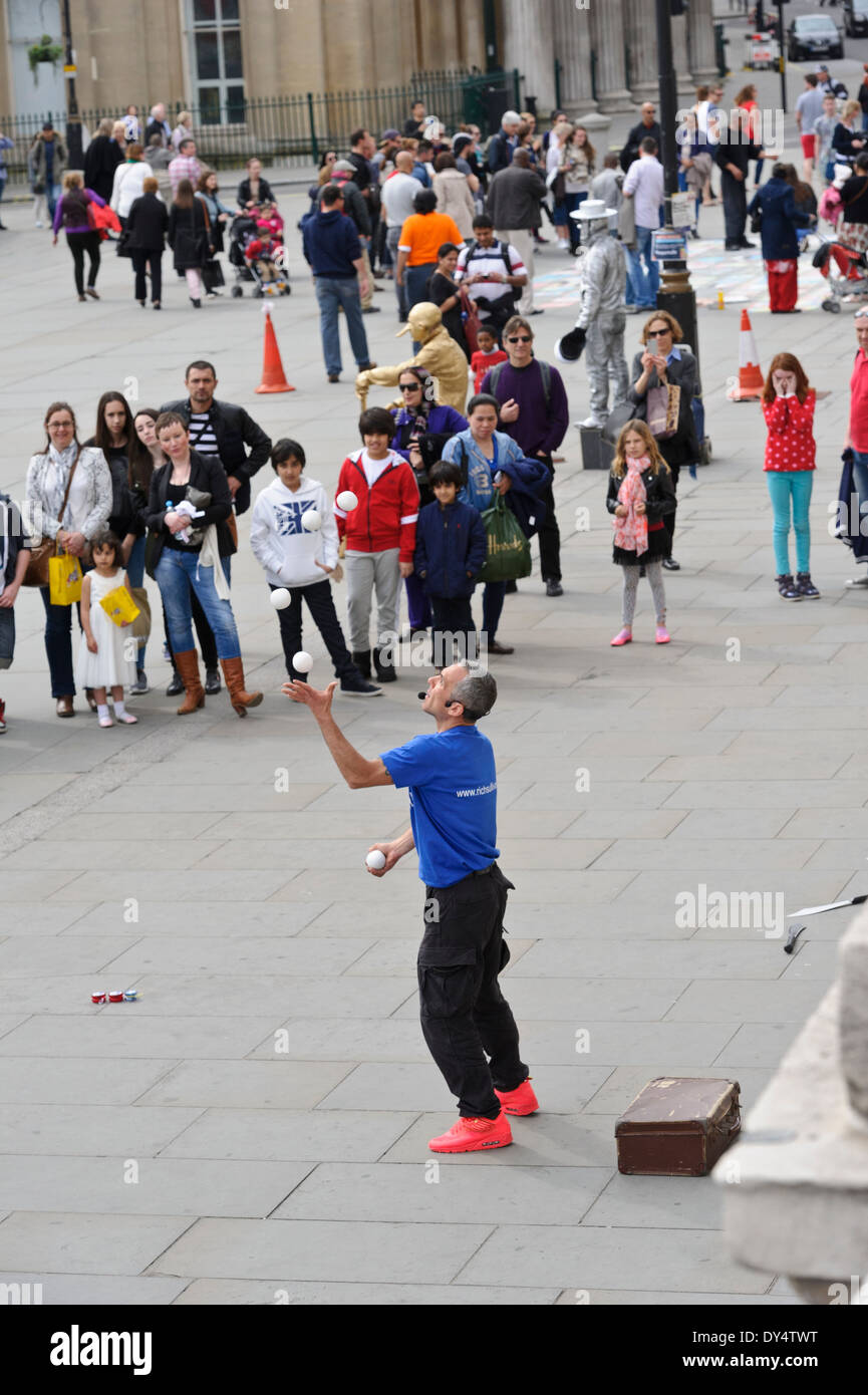 Street Juggler throwing four white balls in the air in front of an