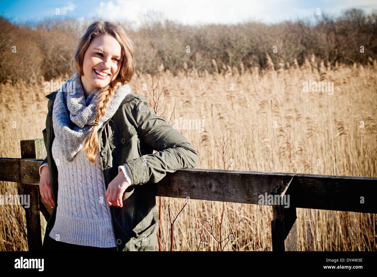Portrait of young woman leaning against fence Stock Photo