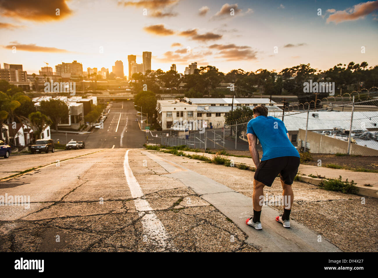 Young male runner taking a break at the top of a steep city hill Stock Photo