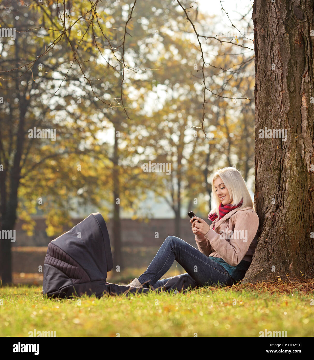 Blond girl texting by phone seated in park Stock Photo