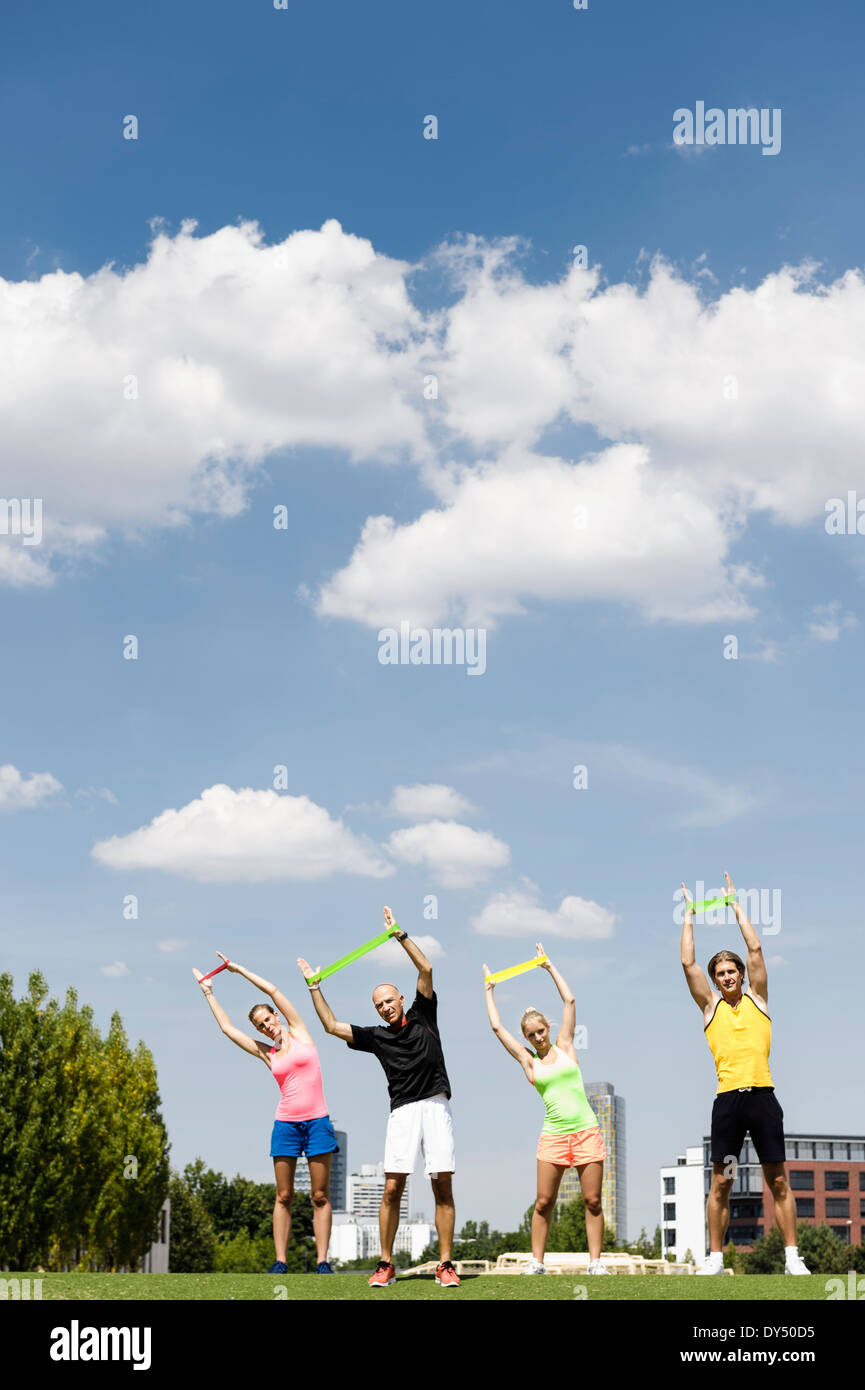 Four people training with rubber exercise bands in park Stock Photo