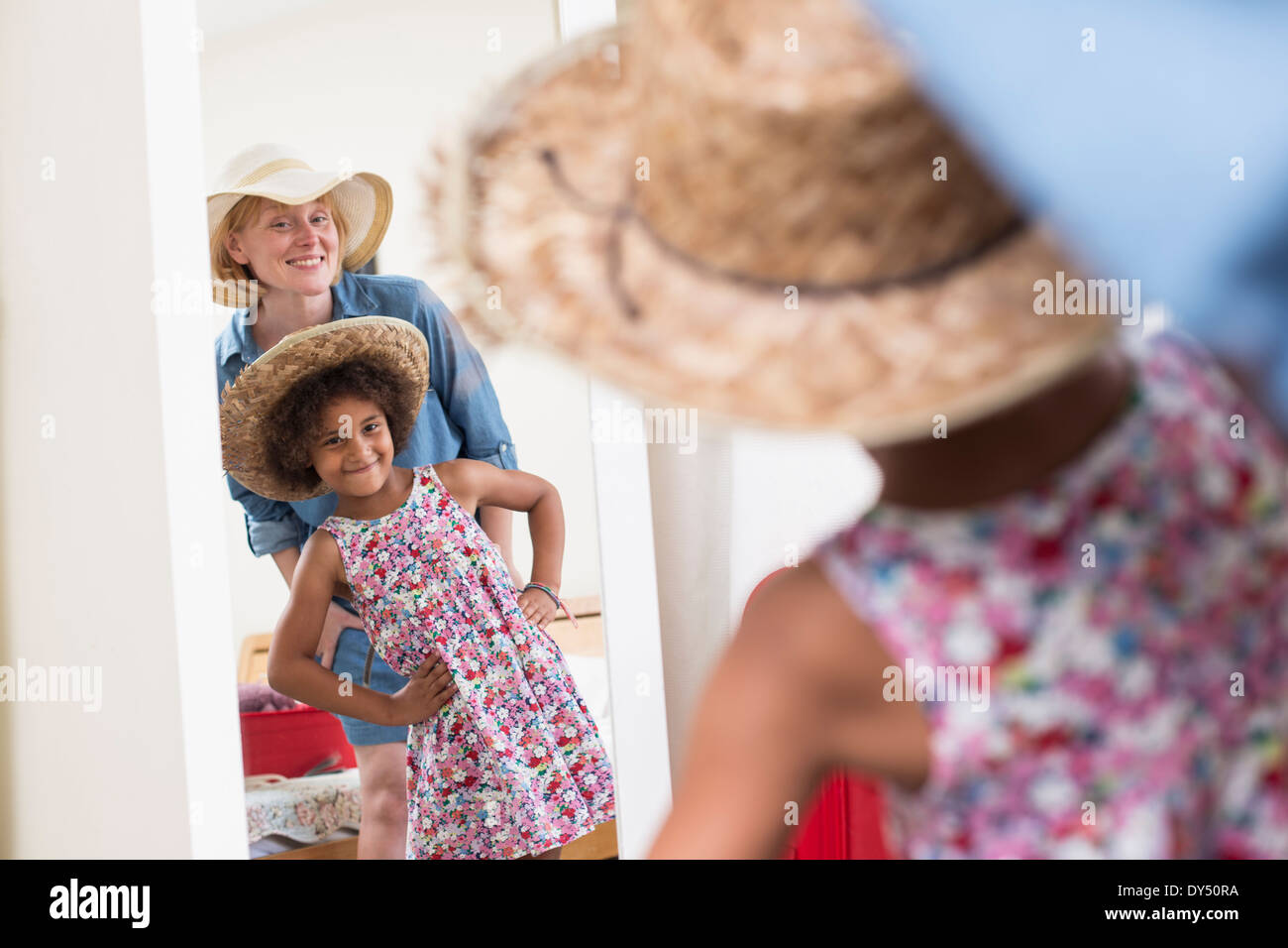 Mother and daughter looking in mirror wearing sunhats Stock Photo