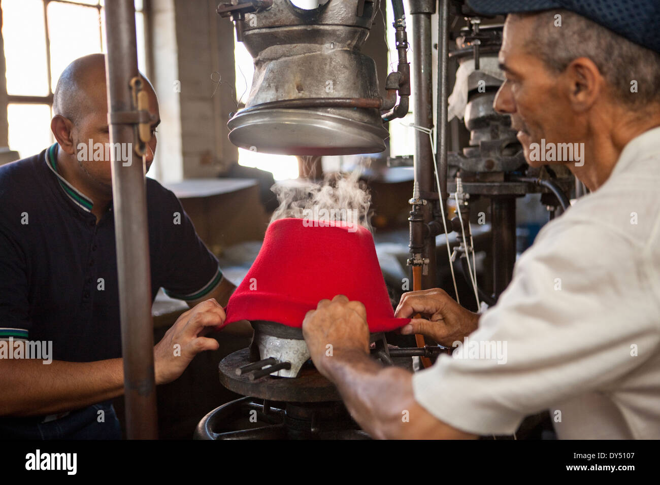 Hat makers pulling fabric onto mould in workshop Stock Photo