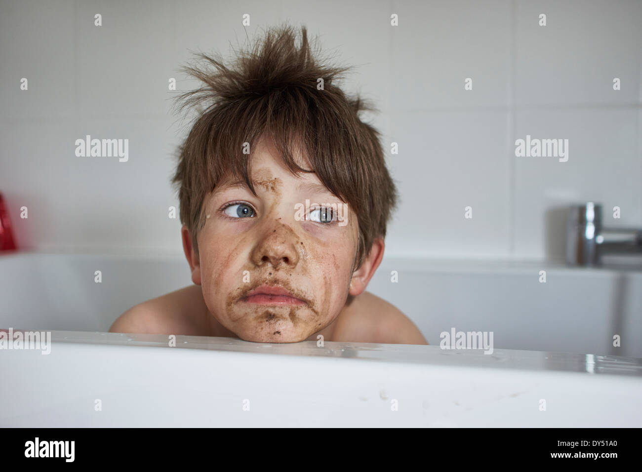 Boy with muddy face, sitting in bath Stock Photo