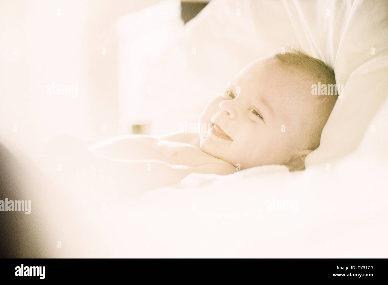 Smiling baby boy lying in crib Stock Photo