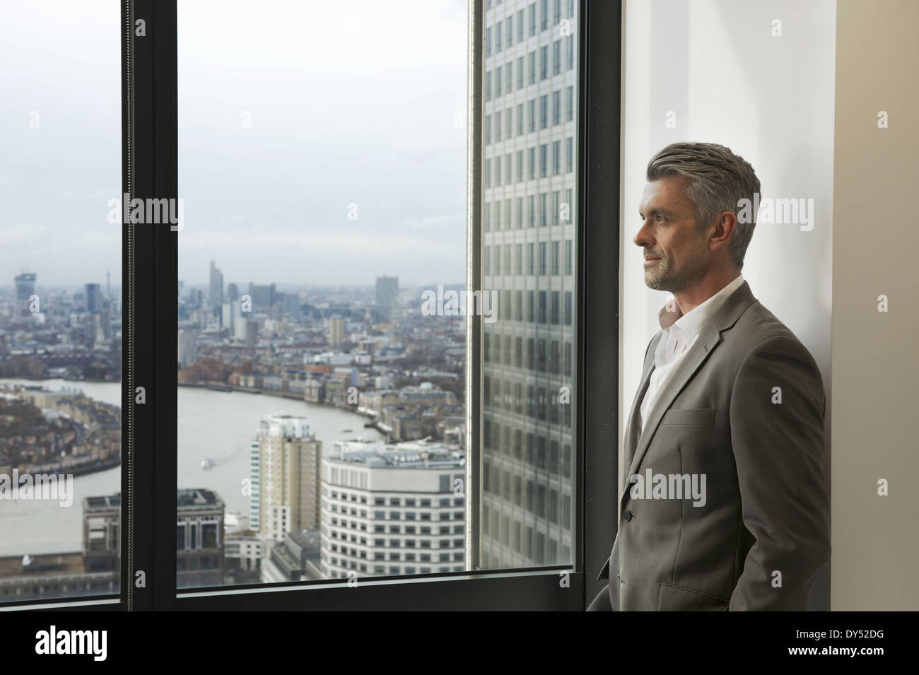 Man looking through window at cityscape stock photo - OFFSET