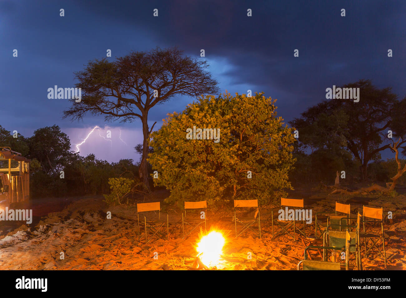 Campfire and a row of empty chairs at night, Kasane, Chobe National Park, Botswana, Africa Stock Photo