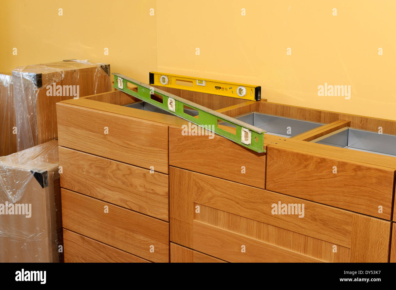 Building a kitchen from ready made units. Levelling units during installation so they line up. Stock Photo