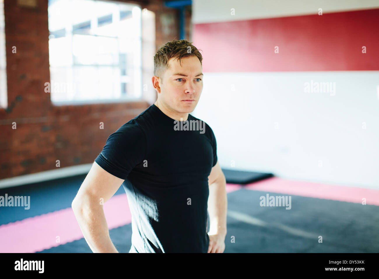 Man standing in gym with hands on hips Stock Photo