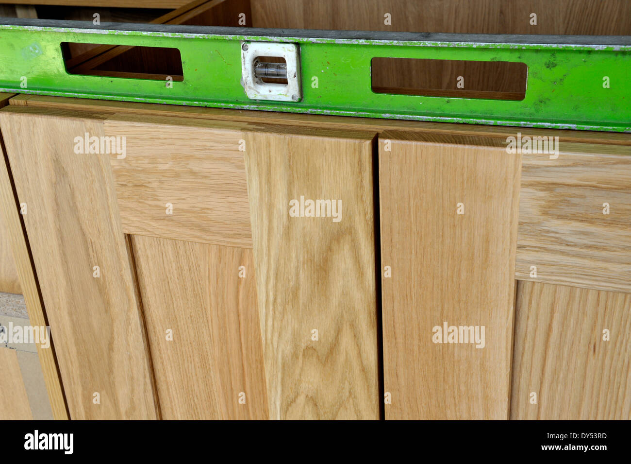 Building a kitchen from ready made units. Levelling between two units with long spirit level Stock Photo