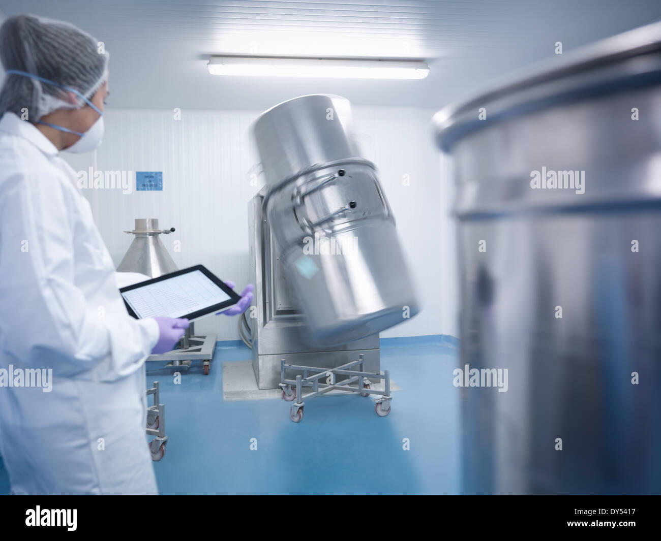 Worker holding digital tablet and watching ingredient mixing machine in