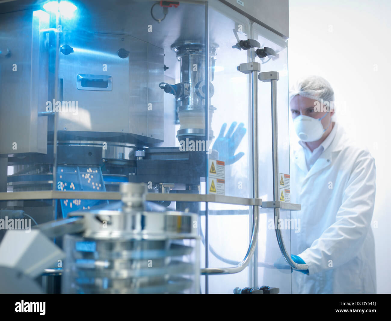 Worker with tablet pressing machine in pharmaceutical factory Stock Photo